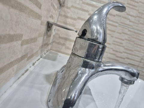 세면대 수전에서 물이 흘러나오는 모습을 가까이서 찍은 사진