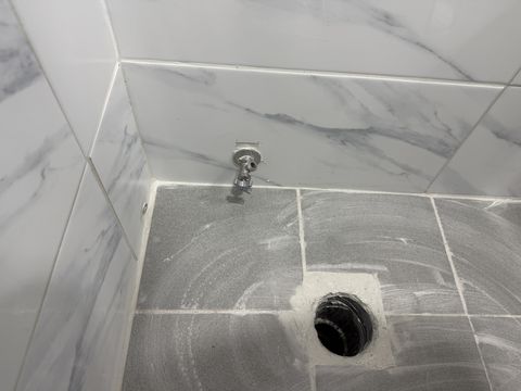 새 타일로 다시 마감한 욕실 바닥과 배수구, 벽 수전