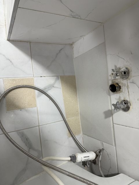 샤워 수전을 떼어 낸 벽의 관 구멍 두 개와 늘어진 샤워 호스