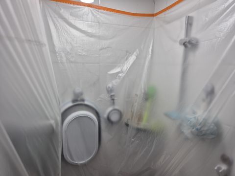 비닐로 덮어 둔 변기와 욕실 벽, 수전