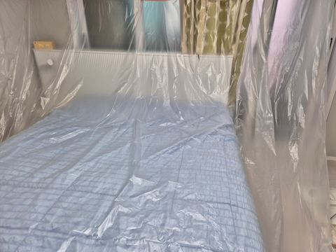 방 안 침대와 벽을 투명 비닐로 덮어 둔 모습