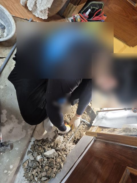 깨어 낸 바닥 속 흙을 손으로 걷어 내는 작업자와 쌓인 자갈