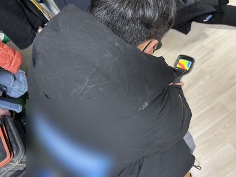 마루 바닥을 향해 열화상 카메라를 든 작업자의 뒷모습