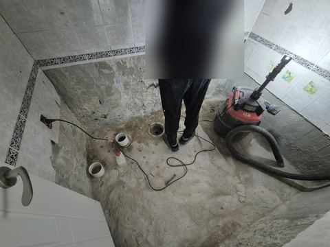 잔해를 걷어 낸 욕실 바닥에 배수구 관 끝이 드러난 모습과 집진기