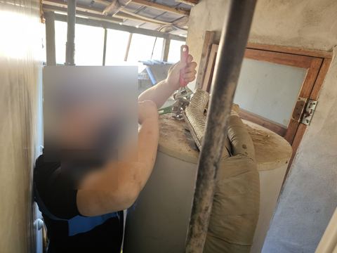 보온재 감은 배관이 이어진 원통형 탱크 상단 연결부를 몽키스패너로 조이는 모습