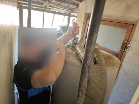 창고 물탱크 상단 보온 배관 이음부를 렌치 두 개로 맞잡아 조이는 모습