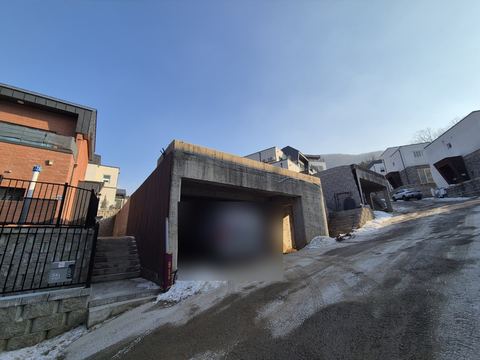 눈이 남은 언덕길 옆 단독주택 차고와 담장
