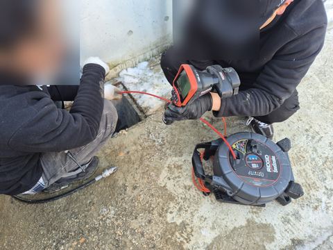마당 바닥 틈에 배관 내시경을 넣고 모니터를 보는 작업자들