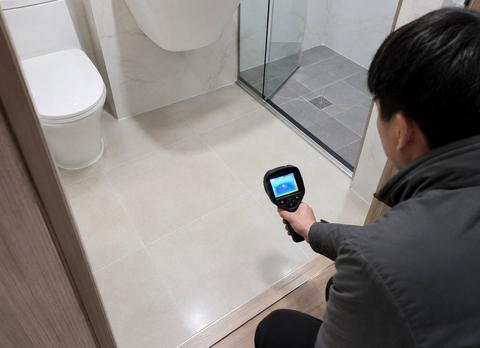 샤워부스 앞 욕실 바닥으로 열화상 카메라를 향한 작업자
