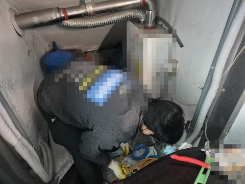 보일러가 달린 좁은 공간에서 몸을 숙여 바닥 쪽 배관을 살피는 작업자
