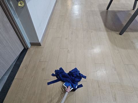 나무무늬 장판 위 파란 밀대 걸레와 군데군데 남은 물기 자국