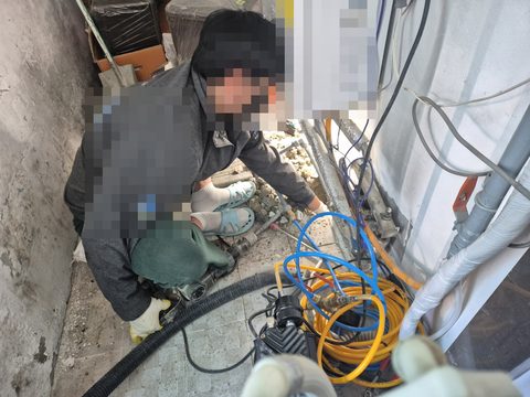 파란색·노란색 호스 장비를 옆에 두고 벽 쪽 배관에 손을 뻗는 작업자