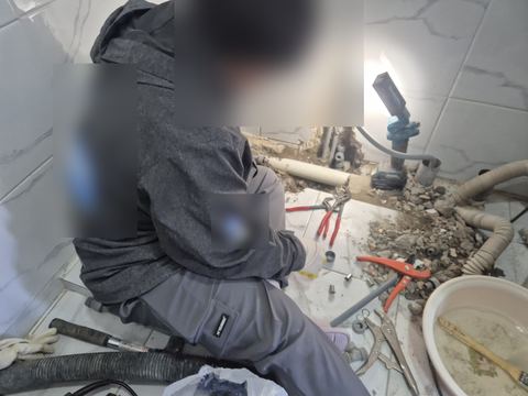 바닥 타일을 깨낸 홈의 흰 배관·회색 급수관 앞에서 부속을 맞추는 손