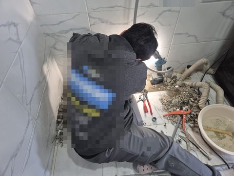 조명을 켜 둔 벽 아래 깨 낸 자리 앞에 앉아 작업하는 작업자 뒷모습