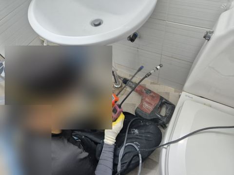세면대 밑 바닥에 앉아 막대형 센서 탐지기 두 대의 화면을 보는 작업자