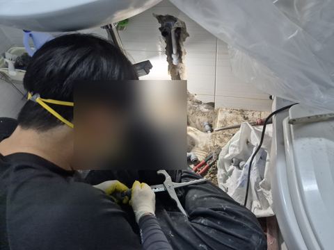 배관 홈을 따낸 욕실 벽 앞, 무릎 위에서 파이프 커터로 관을 다듬는 작업자