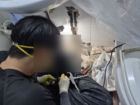 따낸 욕실 벽 앞에서 배관 끝과 피팅을 손에 들고 맞춰 보는 작업자