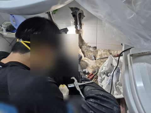 배관 경로를 따라 홈을 낸 욕실 벽과 작업자 무릎 위 파이프 커터