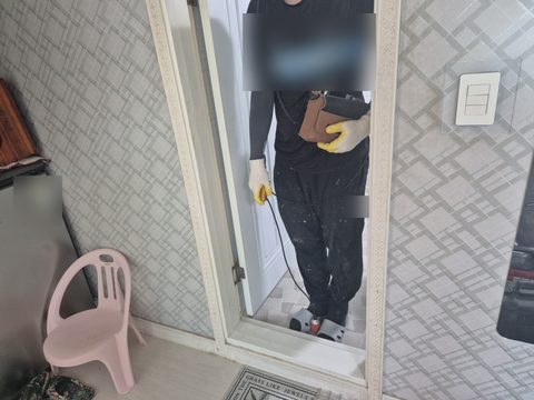 욕실 문간에서 몸에 멘 장비와 이어진 케이블을 손에 쥔 작업자