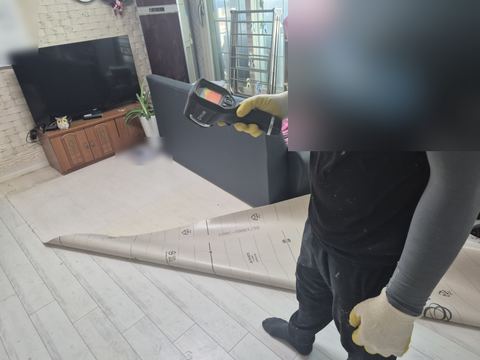 한쪽으로 걷어 올린 장판 옆 바닥을 향한 열화상 카메라와 붉은 온도 표시