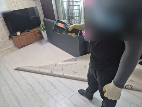 일부 걷힌 장판 위에서 열화상 카메라를 바닥으로 든 작업자