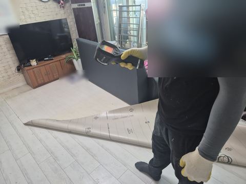 장판 끝을 말아 올린 거실에서 바닥 쪽으로 열화상 카메라를 든 손
