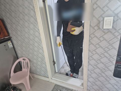 거울에 비친 모습으로 누수탐지기 본체를 어깨에 메고 센서를 쥔 작업자