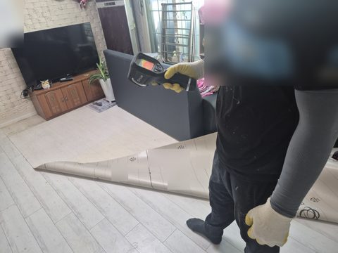장판을 걷어 둔 거실에서 열화상 카메라를 든 작업자